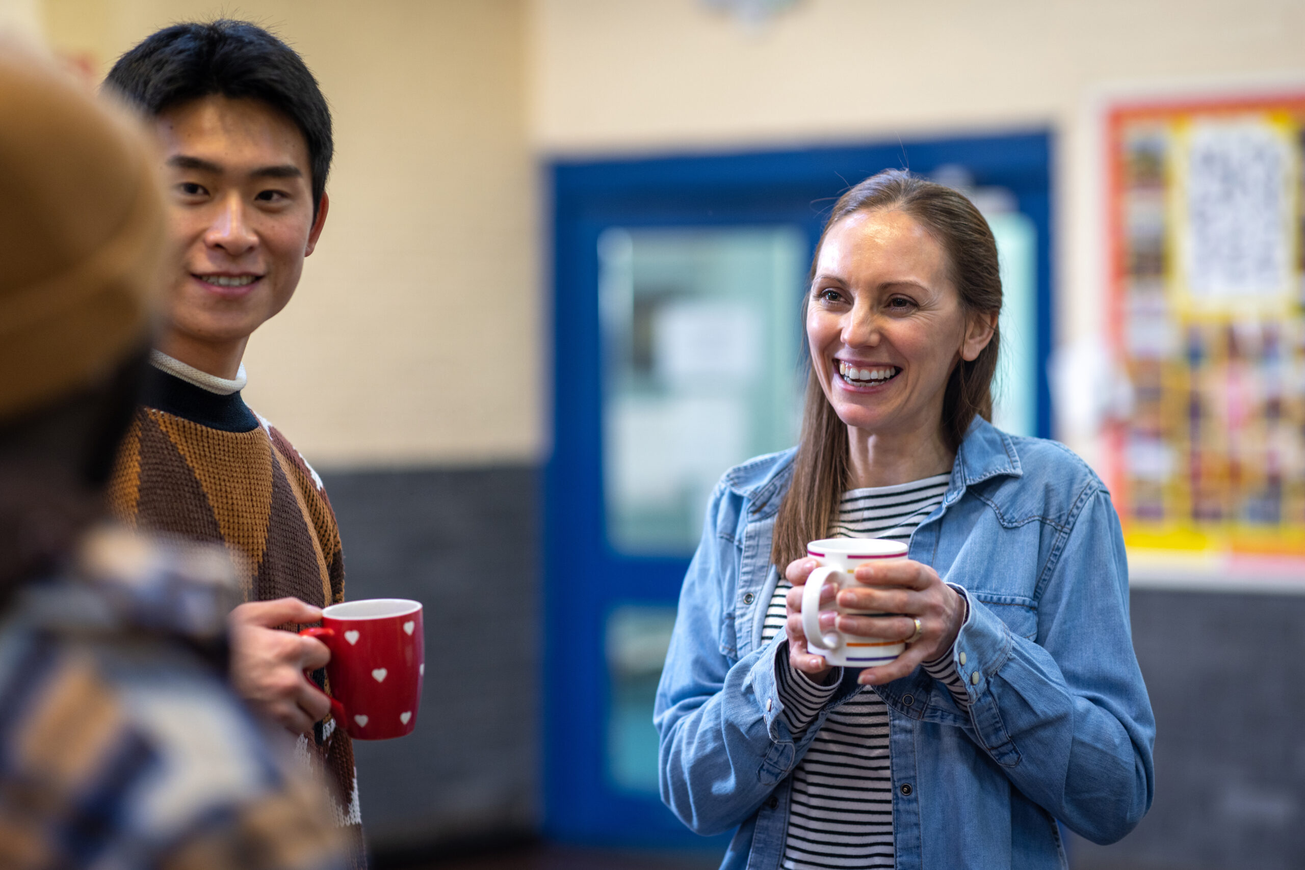 Waist-up shot of a group of adults getting together in a community hall and having a cup of tea together. The community centre is located in Seaton Deleval in the North East of England.