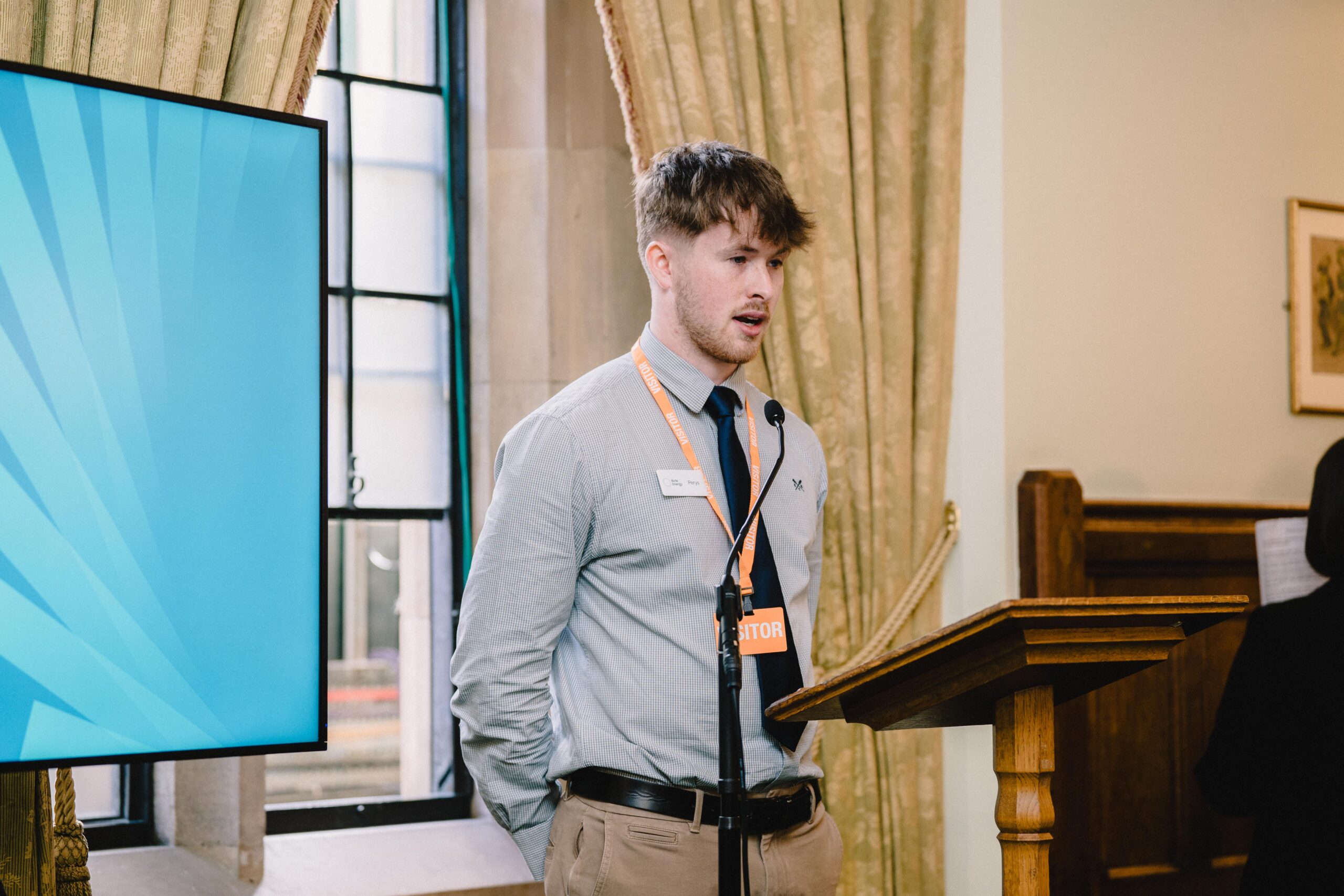 young man wearing a tie speaking at lectern